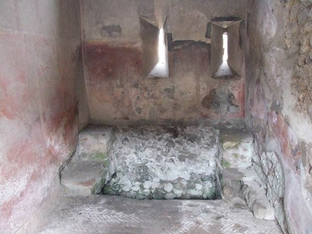 VI.9.6 Pompeii. March 2009. Room 18, large latrine near east wall of kitchen and latrine. According to Hobson, this latrine is just over one metre wide and would have had more than one seat. This would allow for “private” socialisation. See Hobson, B., 2009. Latrinae et foricae: Toilets in the Roman World. London; Duckworth. (p.80) He also states that this latrine possibly would have seated two or three persons.  It had a high decorated dado, painted red, with yellow panels but without motifs. In the area above the dado, a garland of flowers is visible. The floor is a mixture of herringbone and oval tiling. See Hobson, B., 2009. Latrinae et foricae: Toilets in the Roman World. London; Duckworth. (p.86 and fig.110)

