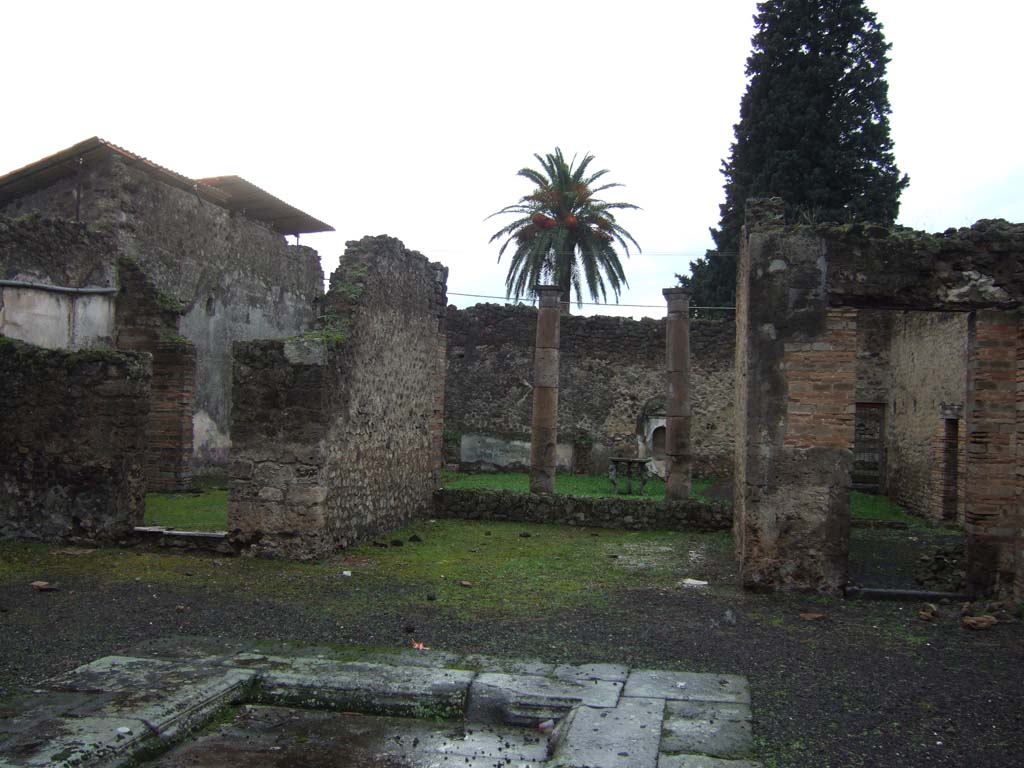 VI.13.13 Pompeii. December 2005. Looking west into doorway of triclinium, and towards doorway to peristyle in rear wall of it.
According to Presuhn, this triclinium (or oecus “c”) would have also had a mosaic similar to the one on the entrance threshold.
In the centre would have been an”emblema”  decorated with rose ornament set into a garland with red, green and yellow polychrome tesserae.



