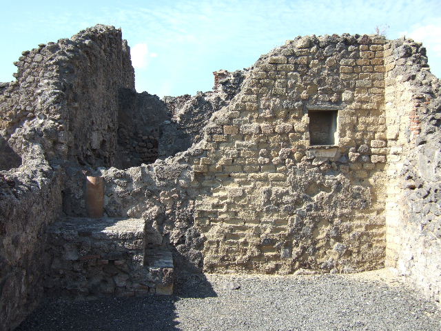 VI.14.4 Pompeii. September 2005. North wall with base of steps to upper floor in north-west corner. Behind the steps can be seen a down-pipe from the upper floor. 
