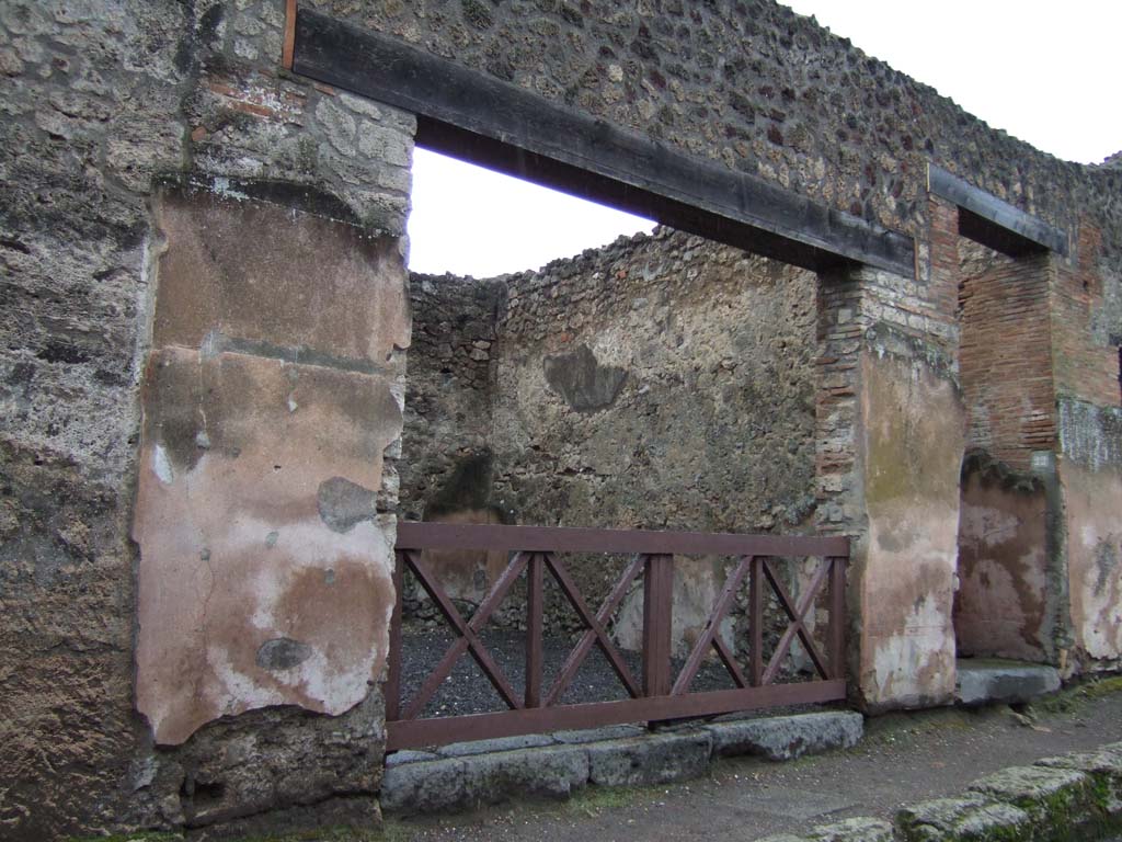 VI.14.21 on the left, and VI.14.22 on the right. Pompeii. December 2005. 
According to Della Corte, these graffiti were found on the front of these entrances:

Caecilium  Capellam
d(uum)  v(irum)  i(ure)  d(icundo)  o(ro)  v(os)  f(aciatis)
Cornelia  rog(at)      [CIL IV 3479]
He thought Cornelia may have been the wife of Vesonius Primus.

[C]n(aeum)  Helvium  Sabinum
aed(ilem)  Primus  cum  suis  rog(at)      [CIL IV 3482]
According to Epigraphik-Datenbank Clauss/Slaby (See www.manfredclauss.de) this graffito ends with the word “fac(iat)” and not “rog(at)”

Also found here was a graffito that read:

Proculum
aed(ilem)  Felicio 
lupinipolus  rog (at)     [CIL IV 3483]

This was similar to the one from the opposite side of the road (see V.1.25 [CIL IV 3423]) and led him to think it named the owner of the shop there.
See Della Corte, M., 1965. Case ed Abitanti di Pompei. Napoli: Fausto Fiorentino. (p.100)

