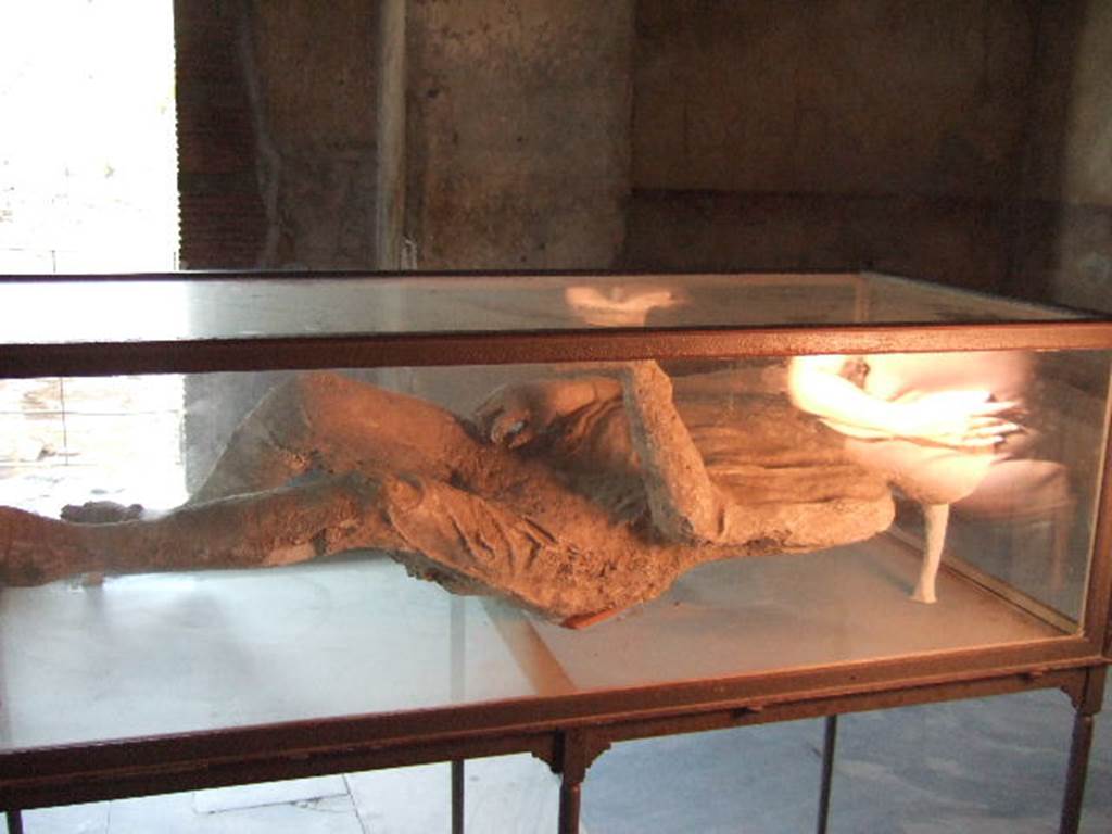Plaster cast of a supine man with arms and legs slightly contracted, wrapped in a cloak.
Found 23rd April 1875 in NE corner of VI.14 in middle of Via Stabiana, four metres above ground level in the ash layer.
He was found next to the woman with her tunic raised over her head.
When photographed, this was on display in VII.1.8, the Stabian Baths, men’s changing room. 
See SSANP: Boscoreale Antiquarium exhibition catalogue: The Casts, 5 March – 20 December 2010. (p.6 and 7)
See Garcia y Garcia, L., 2006. Danni di guerra a Pompei. Rome: L’Erma di Bretschneider. (p.193, Figs 448-9).
  September 2005.