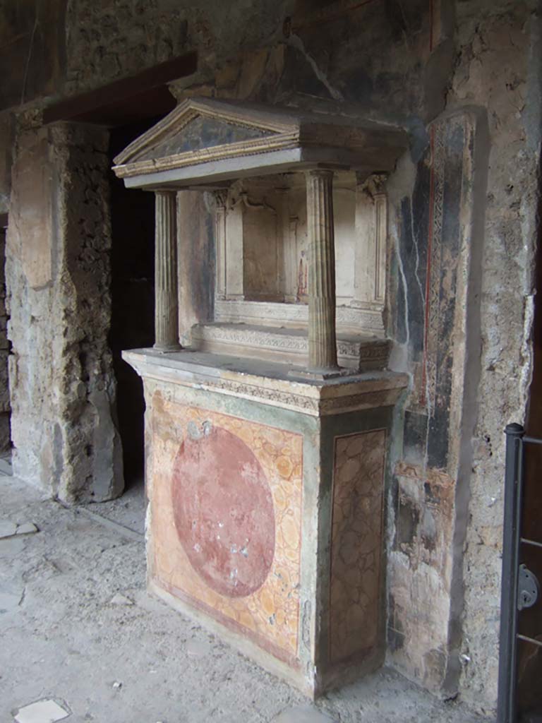 VI.16.7 Pompeii. May 2006. Room F, north portico. Household lararium.
According to Boyce, the shrine was found with its contents intact, and contained the following bronze statuettes:
1. Jupiter – bearded, the upper part of his body nude, the lower part wrapped in a robe. In his right hand the thunderbolt, in the left he probably originally held a sceptre, now missing.
2. Juno – wearing a peplum fastened on her right shoulder and over it a mantle, on her head a high crown.
3. Minerva – wearing a peplum and mantle and on her breast the gorgon, on her head a helmet.
Also found were a statue of Mercury, and the Two Lares.
See Boyce G. K., 1937. Corpus of the Lararia of Pompeii. Rome: MAAR 14, pp. 57-8, no. 221, and pl.38, 2.
