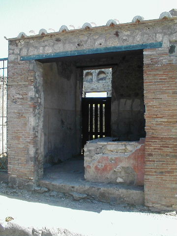 VI.16.33 Pompeii. May 2005. Looking east through wide entrance doorway into bar room C. The walls have a high brick dado, and above this was a simple white plaster. The dado was divided into panels by vertical yellow bands. In the centre of each panel was a painting of a feeding bird, except that on the right of the entrance doorway to the atrium, which showed two birds. At the rear in the east wall can be seen the doorway into the atrium of VI.16.32.
