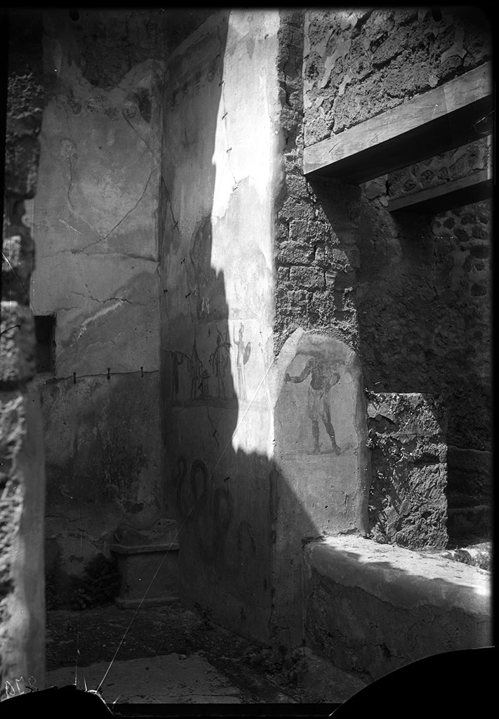 VII.2.14 Pompeii. 1931. North wall with remains of lararium painting with serpent.  
A painting of two gods and two Lares was above this.
See Fröhlich, T., 1991. Lararien und Fassadenbilder in den Vesuvstädten. Mainz: von Zabern. (p283: L80: T40,1.3).
According to Boyce, in the north wall on the east side of the lararium painting, was a window set in a recess which overlooked the kitchen.
On the west wall of this recess, around the corner, was painted a man.
See Boyce G. K., 1937. Corpus of the Lararia of Pompeii. Rome: MAAR 14. (p.61-2, 249, Pl. 23,1) 
DAIR 31.2453. Photo © Deutsches Archäologisches Institut, Abteilung Rom, Arkiv. 
