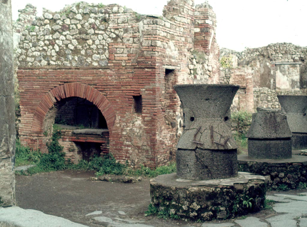 VII.2.22, Pompeii.  August 1976. Detail of oven and mills on south side, looking east.
Photo courtesy of Rick Bauer, from Dr George Fay’s slides collection.
