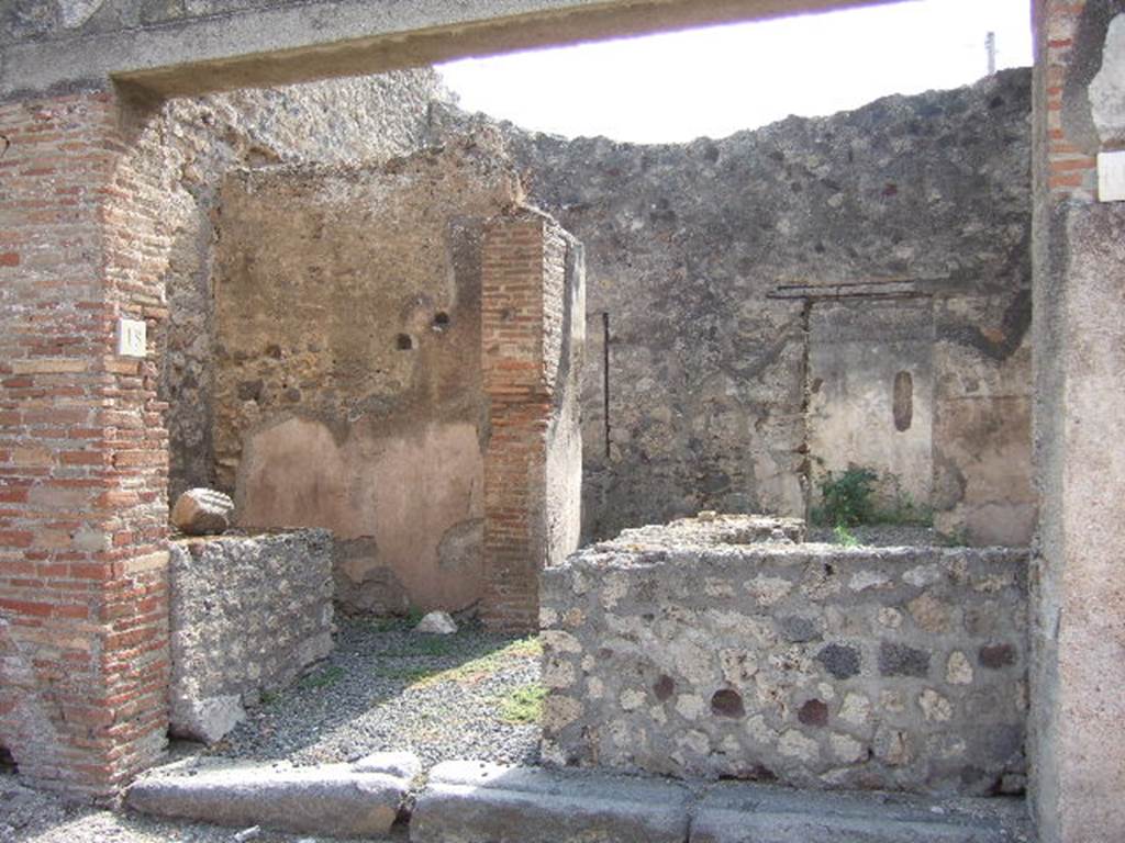 VII.7.18 Pompeii. May 2006. Looking south towards entrance to bar-room.
According to Eschebach, on the left would have been the kitchen with hearth, on the right a two-sided podium with a small oven. In the rear room against the south wall was the base of a wooden stairs to upper floor with a doorway nearby into a triclinium.
See Eschebach, L., 1993. Gebäudeverzeichnis und Stadtplan der antiken Stadt Pompeji. Köln: Böhlau. (p.302)
According to Garcia y Garcia, due to the bombing on the night between 14th and 15th September 1943 many of the rooms suffered from their plaster falling from their walls. The room at the rear, the triclinium, was decorated with an obscene painting, according to Fiorelli, already destroyed by 1875.
See Garcia y Garcia, L., 2006. Danni di guerra a Pompei. Rome: L’Erma di Bretschneider. (p.116)
Also found in the same room was the marble relief, see below.
