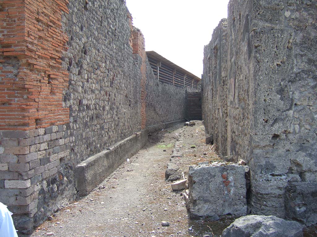 VII.7.23 Pompeii. July 2008. Looking towards outer west wall of small alley, with downpipe. Photo courtesy of Barry Hobson.
