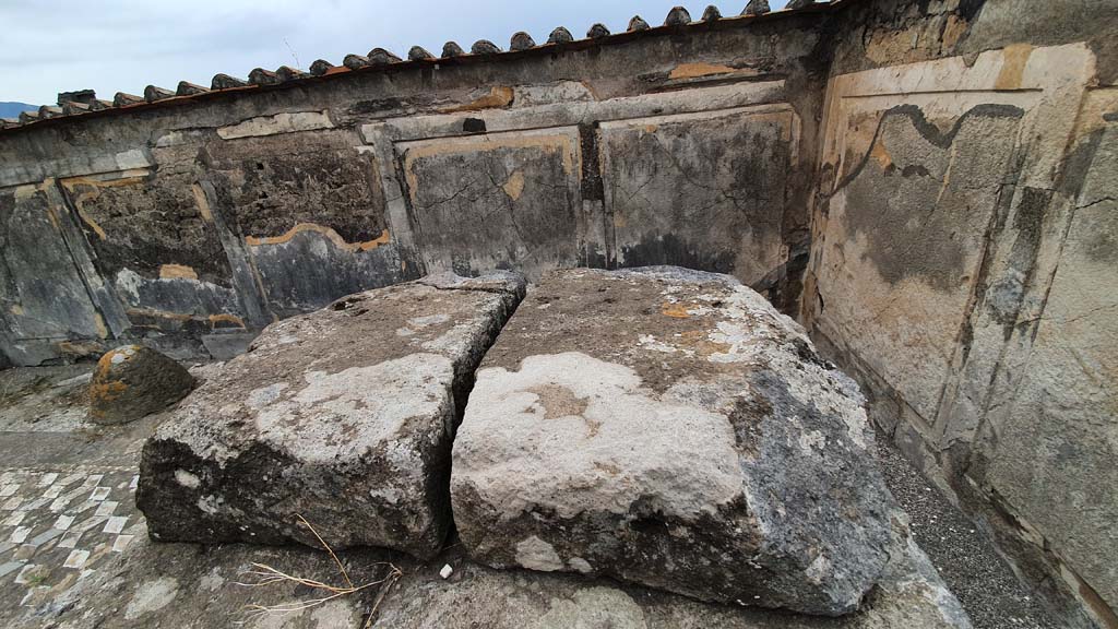 VII.7.32 Pompeii. September 2019. Looking east along north side of colonnade. Photo courtesy of Klaus Heese.
The doorway to the rear room, known as the room of the priest, or chamber of Bacchus, would have been in the north wall on the left.
Cooke, Cockburn, and Donaldson wrote -
“At the end of the court, opposite the entrance, was a small chamber, which possesses an invaluable picture of Bacchus and Silenus, the former holding the thyrsus in one hand and a vase in the other; Silenus appears with his lyre instructing the god. A small niche is in the wall, apparently for the reception of a statue or lares.”
See Cooke, Cockburn, Donaldson: Pompeii, Pt 1, 1827, (p.55)
According to Garcia y Garcia –
“Because of the bombardment in 1943 there was much damage to the temple: it was hit by two bombs during the night of 13th September, when the west portico with the demolition of part of the stylobate, four columns and the demolition of an 8m part of the perimeter wall to the west were hit. Hit again by a successive incursion, there followed the demolition of the north-east corner of the portico with fallen and partial loss of the IV Style painted plaster; the felling of part of the north perimeter wall, of four columns from the north portico and of the stylobate that surrounded the temple. The rear room to the north of the portico was completely destroyed. The painting of Bacchus and Silenus is now in the Naples Archaeological Museum.”
This small room, perhaps used by the priest, became to be known as the chamber of Bacchus.
See Garcia y Garcia, L., 2006. Danni di guerra a Pompei. Rome: L’Erma di Bretschneider. (p.111-112).



