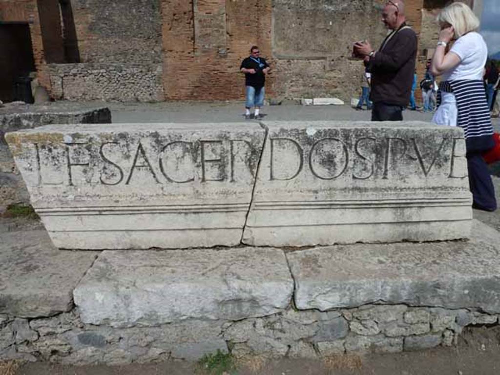 VII.8 Pompeii Forum. May 2010. Part of the Latin inscription in large letters on the entablature of the portico, reading -
L. F. SACERDOS PUB

The full inscription was similar to the one above the entrance at VII.9.67:
EUMACHIA L. F., SACERD(OS) PUBL(ICA), NOMINE SUO ET 
M. NUMISTRI FRONTONIS FILI CHALCIDICUM, CRYPTAM, PORTICUS CONCORDIAE 
AUGUSTAE PIETATI SUA PEQUNIA FECIT EADEMQUE DEDICAVIT.
See Mau, A., 1907, translated by Kelsey F. W. Pompeii: Its Life and Art. New York: Macmillan. (p.111)

Eumachia, daughter of Lucius, public priestess, in her own name and that of her son, Marcus Numistrius Fronto, built at her own expense the chalcidicum, crypt and portico in honour of Augustan Concord and Piety and also dedicated them. 
See Cooley, A. and M.G.L., 2004. Pompeii : A Sourcebook. London : Routledge. (p.100, E42) 

