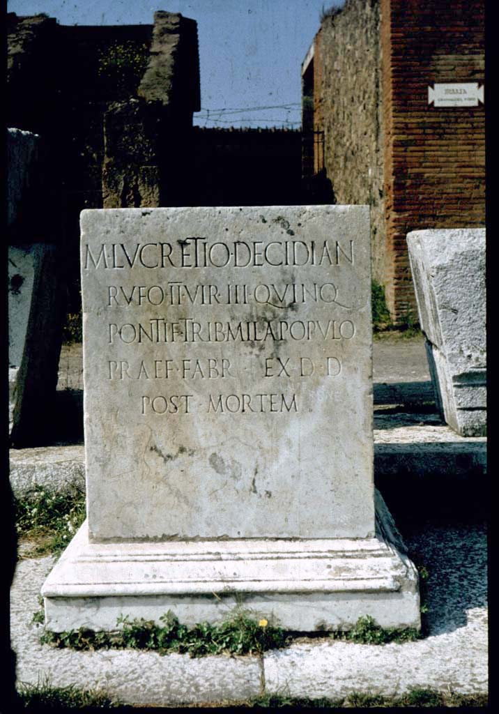 VII.8 Pompeii Forum. May 2010. Pedestal base for statue, decorated with bull's heads and flower motifs. This has the Latin inscription –

M .  LVCRETIO . DECIDIAN
RVFO . D . V. III . QVINQ
PONTIF . TRIB . MILITVM
A POPVLO . PRAEF . FABR
M . PILONIVS . RVFVS

See Pappalardo, U., 2001. La Descrizione di Pompei per Giuseppe Fiorelli (1875). Napoli: Massa Editore. (p. 101)

According to Pagano and Prisciandaro, this was found in June 1816, it read –

M(arco) Lucretio Decidian(o)
Rufo d(uum)v(iro) III quinq(uennali)
pontif(ici) trib(uno) militum
a populo praef(ecto) fabr(um)
M(arcus) Pilonius Rufus     [CIL X 788]

See Pagano, M. and Prisciandaro, R., 2006. Studio sulle provenienze degli oggetti rinvenuti negli scavi borbonici del regno di Napoli. Naples: Nicola Longobardi.  (p.114)   
PAH III, 7.

According to Cooley, this translates as

To Marcus Lucretius Decidianus Rufus, duumvir three times, quinquennial, priest, military tribune by popular demand, staff officer. Marcus Pilonius Rufus set this up.

See Cooley, A. and M.G.L., 2004. Pompeii: A Sourcebook. London: Routledge. F92, 0. 130.
