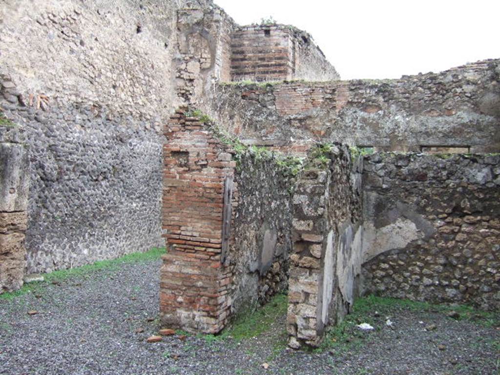 VII.9.40 Pompeii. December 2005. Three doorways on north side of atrium. On the left the doorway to the triclinium with a window onto the garden at the rear. In the centre, a corridor leading north to doorway to garden area, stairs to upper floor, and a cubiculum with window overlooking the garden. On the right, the tablinum. The stairs to the upper floor would have been behind the tablinum. According to Jashemski, this narrow shop-house, which reached through the entire insula, had a large shop fronting onto Via degli Augustali, a little wool-scouring plant (VII.9.41) and separate entrance doorway on the Vicolo del Balcone Pensile leading to the home of the owner, in the middle.
The garden was at the rear of the living quarters. It had a garden painting on the south wall which was visible from the Via degli Augustali through a very wide opening in the rear room of the shop. Little remains of the garden today. There was also a fountain, mentioned by Fiorelli and Niccolini, but there are scant remains of it today. A door from the living quarters led into the garden, and both the triclinium and a cubiculum had a large window opening into the garden. The large opening in the rear room of the shop also showed that the garden was intended to be enjoyed by those in the shop at VII.9.27.
See Jashemski, W. F., 1993. The Gardens of Pompeii, Volume II: Appendices. New York: Caratzas. (p.189)
Jashemski also noted that the garden painting on the south wall of the garden was not mentioned in any of the reports. In 1961, when she cleaned the brambles from this garden, on the wall between the door and the window of the cubiculum, she found the painting of a low garden fence with painted plants still visible above it. Behind the fence was painted a fountain supported on three slender legs. There were also faint traces of what appeared to be a similar fountain beyond the painted fence on the opposite side of the door, and perhaps another on the other side of the cubiculum window.
See Jashemski, W. F., 1993. The Gardens of Pompeii, Volume II: Appendices. New York: Caratzas. (p.363-4, no.79)

