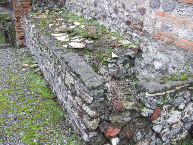 VII.10.5 Pompeii. December 2005. Podium and tub for heating a vat, against south wall of peristyle.    According to Amoroso, the installation of the workshop (“officina lanifricaria”) determined the transformation of the peristyle, whose south side was filled with counters and by basins set in masonry.  The ample portico space was transformed from a walkway to represent a working courtyard, and probably given a gallery, which was accessed by a ramp located in an alcove described by Fiorelli.
Studi della Soprintendenza archeologica di Pompei, 22: l”Insula VII, 10 di Pompei , by Angelo Amoroso. (p.80)


