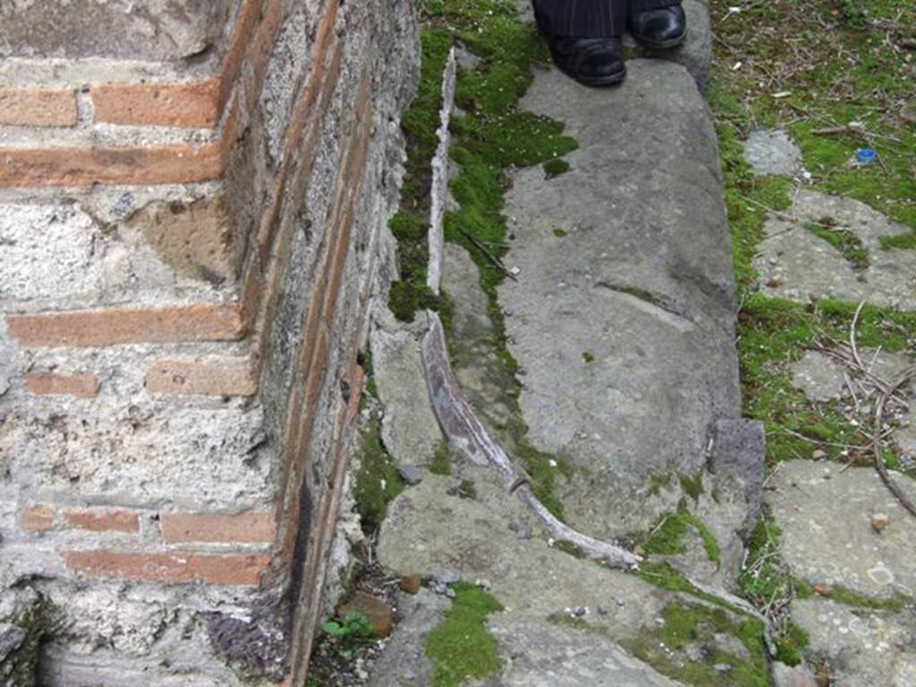 VII.10.9 Pompeii.  March 2009.  Lead pipe in pavement outside entrance, in Vicolo del Balcone Pensile.