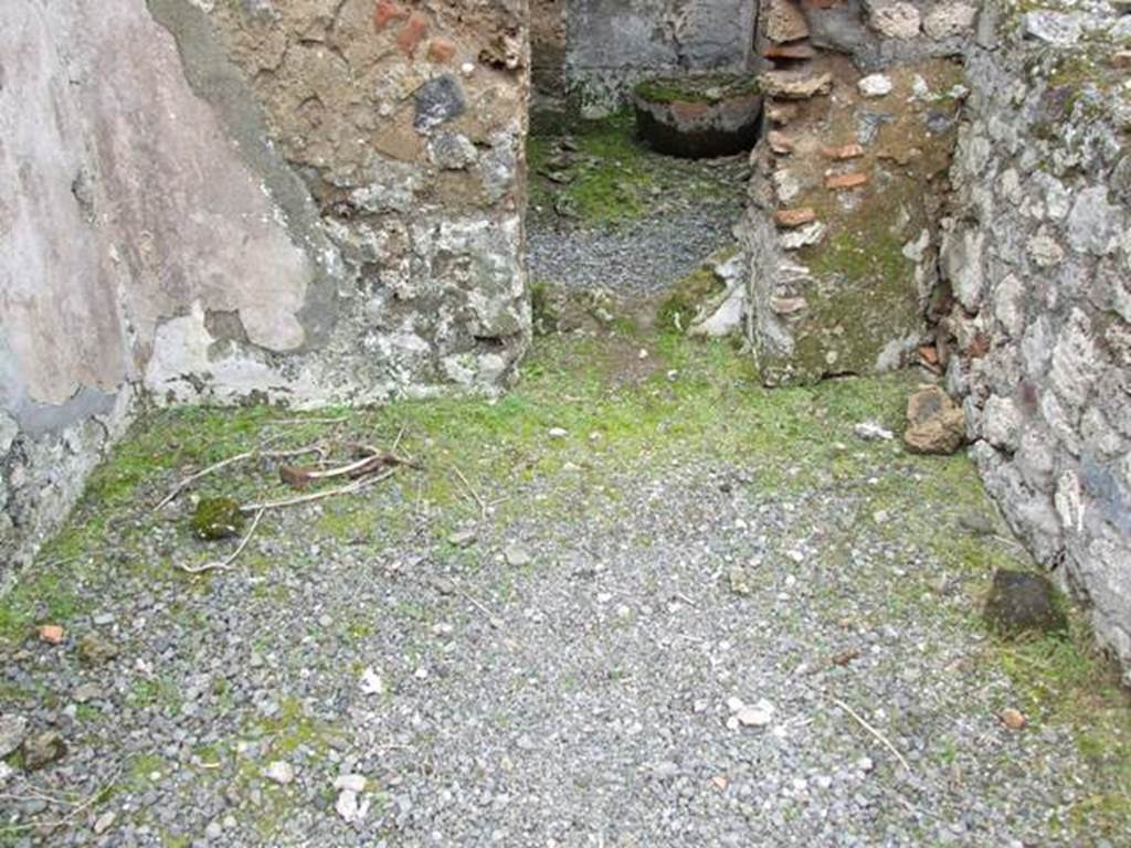 VII.10.12 Pompeii.  March 2009. Looking west at floor and wall with a door with plaster in the lower area.