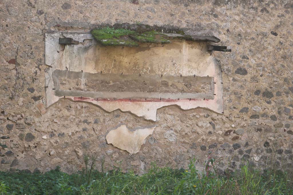VII.10.14 Pompeii. December 2018. Painted decoration on south wall. Photo courtesy of Aude Durand.
According to Jashemski, this was a badly preserved painting with plants and birds that were still faintly visible in l993.
See Jashemski, W. F., 1993. The Gardens of Pompeii, Volume II: Appendices. New York: Caratzas. (p. 191)
Boyce reported there was a garden painting on the north wall, and in front of it was a masonry altar with a step on the front of it.
Boyce said the wall was painted with trees, plants and birds. 
The altar was coated with white stucco and decorated with the following painted objects.
On the front side, a shallow dish with fruits and a pine cone. 
On the left side, two trees with an altar between them, with the attributes of Diana around it, a crown, a bow, a quiver, two hunting spears, two dogs and a torch. 
On the right side, a rural shrine scene consisting of a column and capital, and on the top of the capital a basket containing two rhyta, a jar, a phallus-like object covered with a red cloth; across the field was painted a thyrsus.
See Boyce G. K., 1937. Corpus of the Lararia of Pompeii. Rome: MAAR 14. (p. 69) 
According to Amoroso, this is the lararium painting [on the south wall].
See Studi della Soprintendenza archeologica di Pompei, 22: l'Insula VII, 10 di Pompei, by Angelo Amoroso. ((p.111, fig. 40a)
