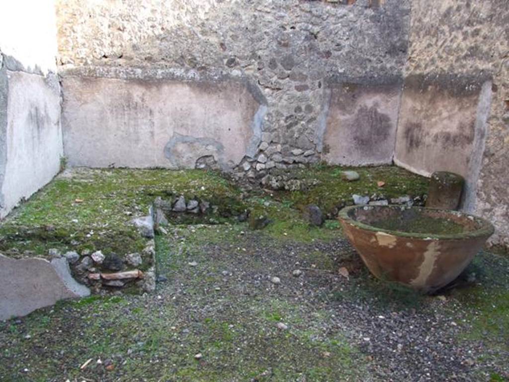 VII.11.5 Pompeii. December 2007. Podium with remains of hearth and large terracotta pot for washing the cloth.