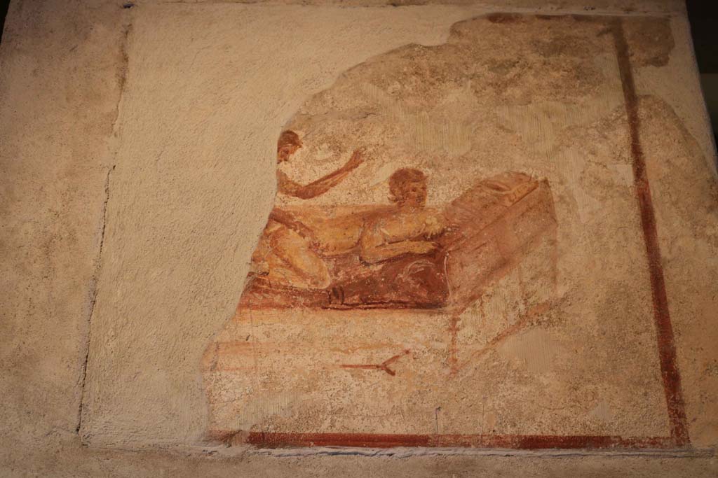 VII.12.18, Pompeii. December 2018. 
Wall painting of Priapus in front of a fig tree, with double phallus, from the upper frieze in the middle of the north wall.
Photo courtesy of Aude Durand.
