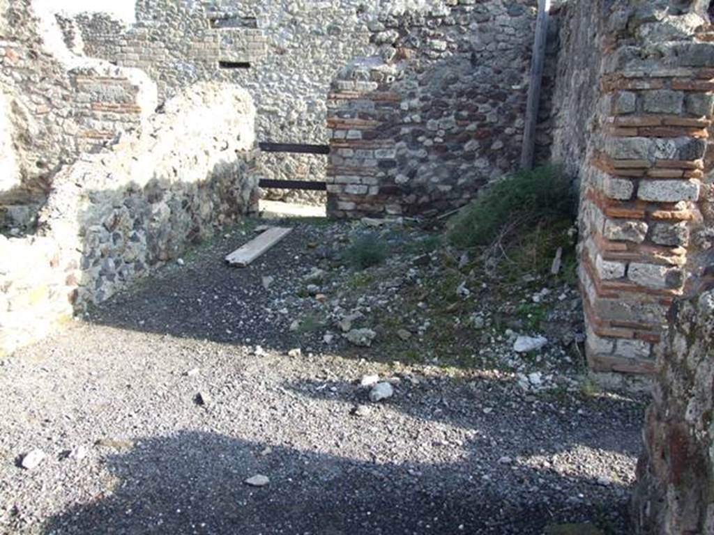 VII.13.9 Pompeii. December 2007. Looking east across kitchen with remains of hearth (under greenery) and posticum doorway at VII.13.12.