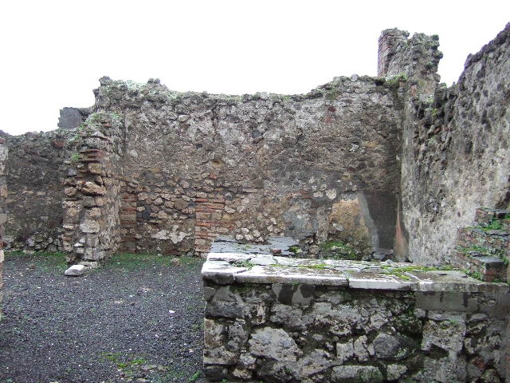 VII.13.24 Pompeii. December 2005. Looking east across two-sided counter, with hearth. On the left is a doorway into a side room.
