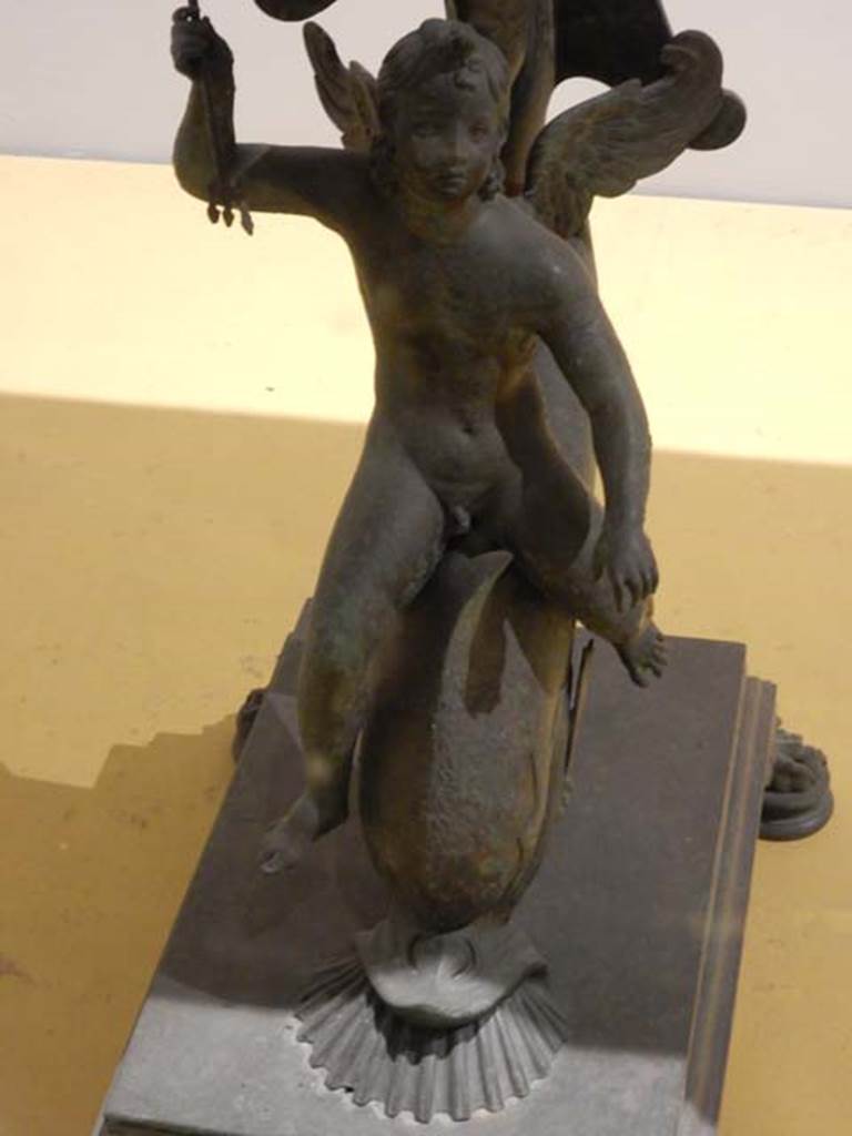VII.16.17-22, Pompeii. House of Fabius Rufus. April 2019. Lamp and statuette. In exhibition in Antiquarium.
Oil lamp with Jupiter and eagle on the handle, and Jupiter, Juno and Minerva in the central part. PAP inventory number 13962.
Bronze statuette of Mercury carrying a sack of coins. PAP inventory number 13987.
Photo courtesy of Rick Bauer.
