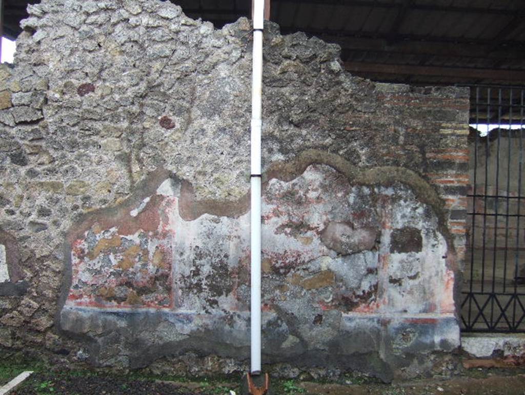 VIII.2.24 Pompeii. December 2005. South wall of bar, with doorway into palestra.
On the right, near the doorway, the black zoccolo (lower wall or dado) still retains the red border of one of its panels. The middle area of the wall would have had simple red panels separated by black compartments.
