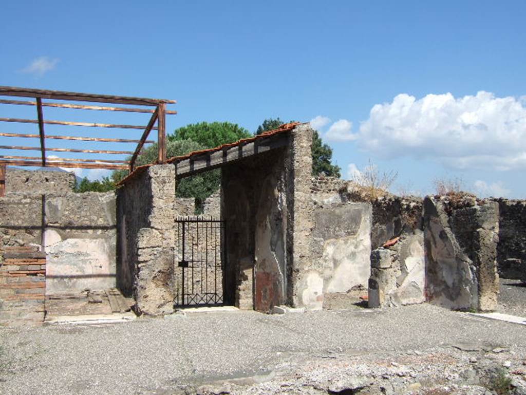 VIII.2.26 Pompeii. September 2005. Looking north across atrium ‘d’ to entrance doorway.
When excavated, the large impluvium was already missing its coating, probably of marble. 
In the centre it would have had a fountain fed by a pipe that entered below the floor in the north-east corner, where the large hole remains unrestored. On the right can be seen the remains of the black floor mosaic with inset large stones of white tesserae and a border of two white lines.
