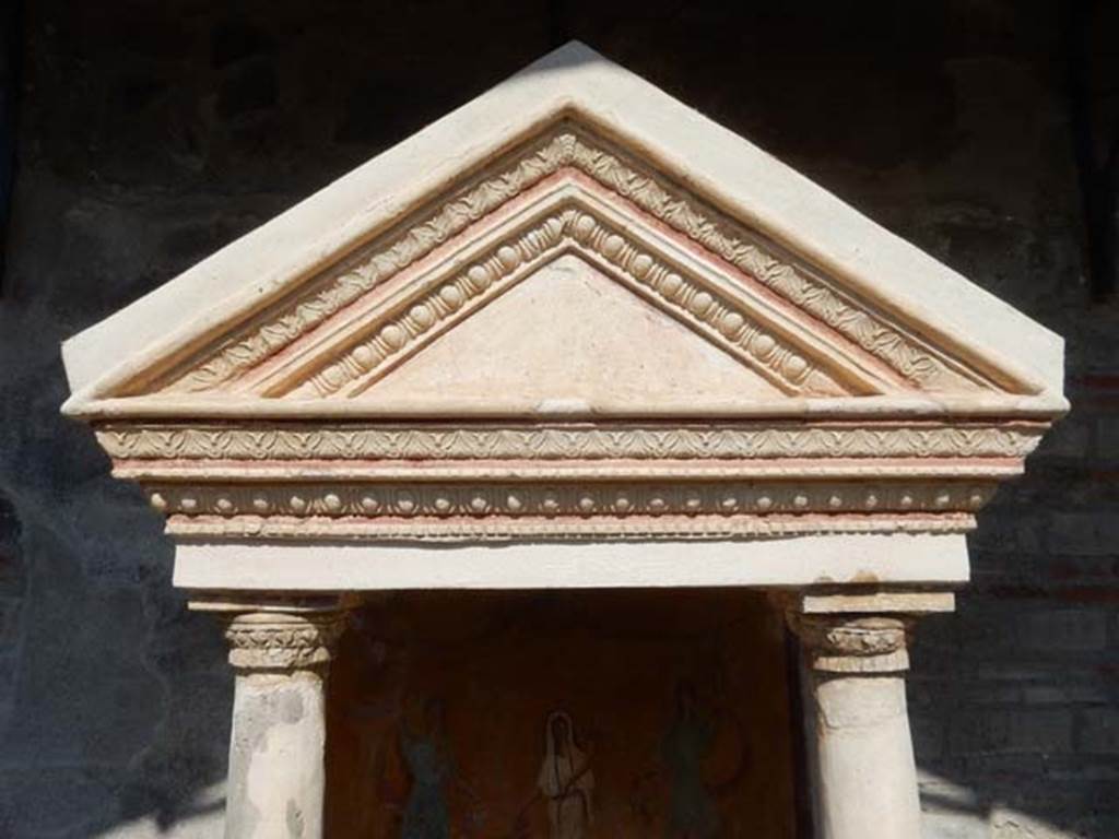 VIII.5.37 Pompeii. May 2017. Detail of the aedicula lararium and ornamental triangular panel.  The tympanum (the triangular panel) was white, and bordered with a red stripe and painted on it when found were small gladiatorial arms. In the middle a helmet, to the left greaves, and to the right a shield and above it a dagger. Photo courtesy of Buzz Ferebee.
