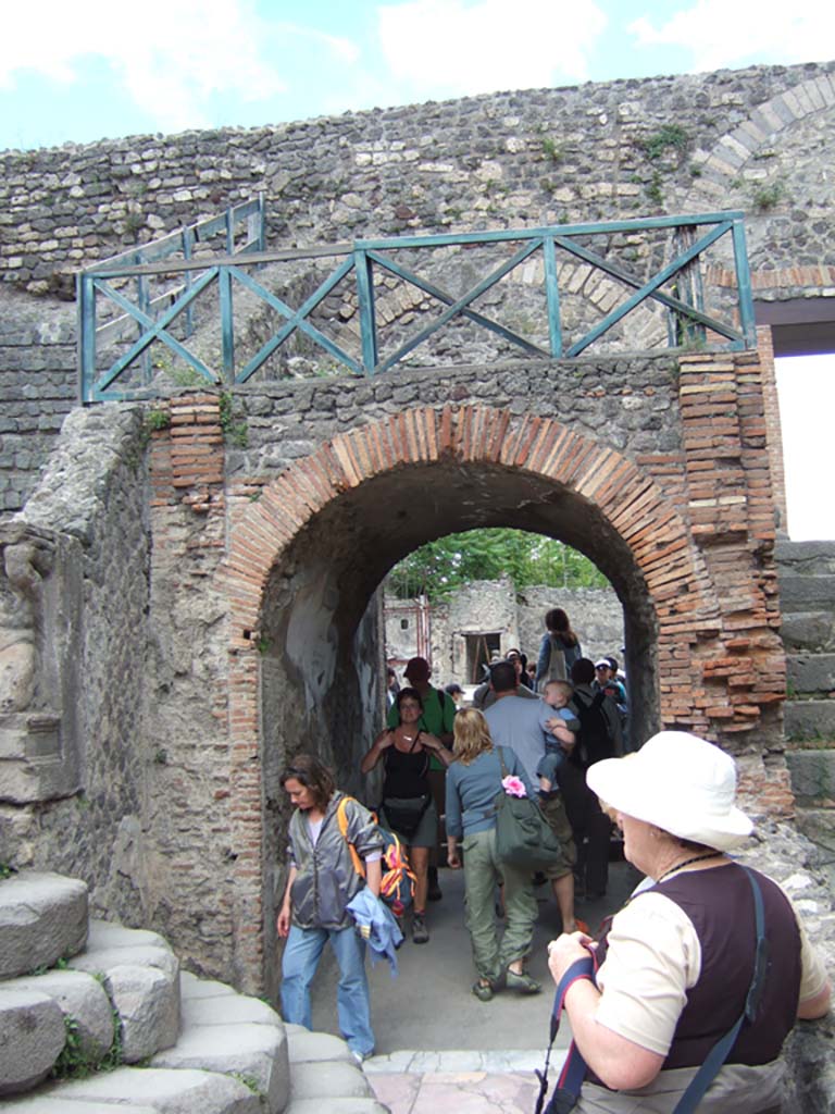 VIII.7.19 Pompeii. May 2006. East side with arched entrance. 
Above the entrances on either side were the rectangular areas which had the seats reserved for the honoured guests. 
These were called the Tribunals. 
These were reached by the small narrow steps at the side and separated from the rest of the audience by a sloping wall to the north.  
The Kneeling Atlas and Lion’s foot were at the lower end of this sloping wall on both the West and East sides.
