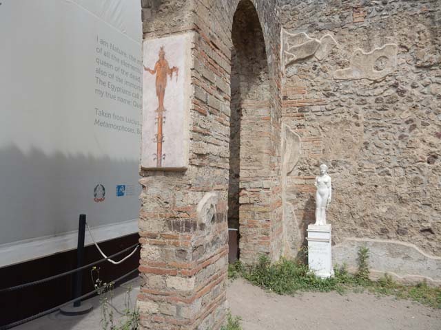 VIII.7.28 Pompeii. May 2017. North-west corner of portico with reproductions of the statue of Isis and a candelabra fresco on the north wall of the second arch from the north in the Ekklesiasterion.
Photo courtesy of Buzz Ferebee.

