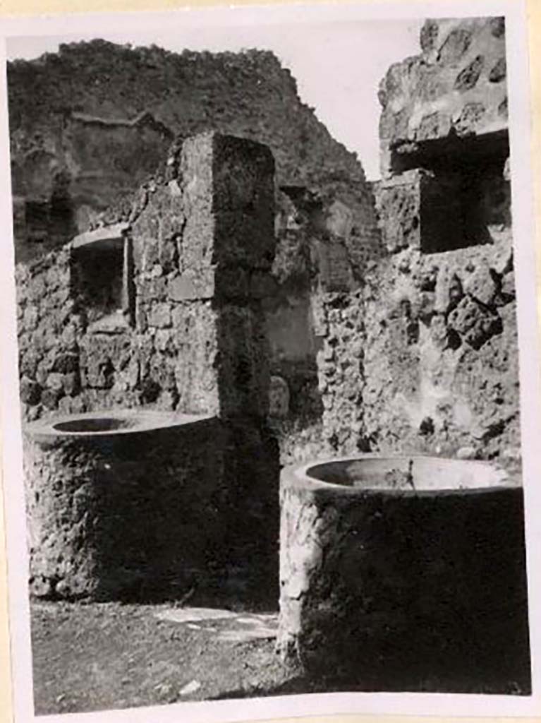 IX.1.3/33 Pompeii. Pre-1943. 
Looking south-west from oven towards two small tubs, above both were niches. Photo by Tatiana Warscher.
See Warscher, T. Codex Topographicus Pompeianus, IX.1. (1943), Swedish Institute, Rome. (no.9), p. 22.
According to Boyce 
Against the wall facing the oven stand two small masonry basins and in the wall above each is a rectangular niche called by Fiorelli la nicchia dei Penati; there remains today no indication of religious purpose.
See Boyce G. K., 1937. Corpus of the Lararia of Pompeii. Rome: MAAR 14, (379).
