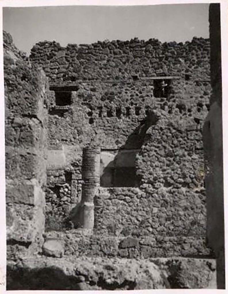 IX.1.12 Pompeii. Pre-1943. Photo by Tatiana Warscher.
Looking across peristyle towards doorway to cubiculum in north-east corner of peristyle. 
According to Warscher, the rear (east) wall had rectangular holes for support beams which demonstrated that there were rooms on an upper floor. 
These rooms would have received light through windows from IX.1.20. 
See Warscher, T. Codex Topographicus Pompeianus, IX.1. (1943), Swedish Institute, Rome. (no.52), p. 82.

