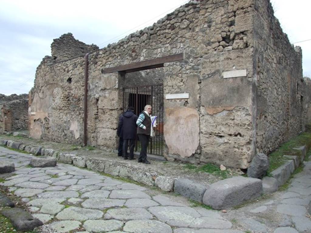 IX.3.19 Pompeii. December 2007. Entrance doorway. According to Fiorelli, “the shop communicated with a bakery, whose doorway was in the eastern roadway (IX.3.20).
It seemed to have been used for the sale of bread, and next to the entrance threshold of the doorway, was a shallow masonry parapet/podium for the mortar, on the other side were the marks for the staircase to the upper floor, under which was installed a storeroom/cupboard with three tiers of shelves. There were two tricliniums lit by windows, the first of which was decorated with two figures of Baccantes, one with thyrsus in hand and a basket on the head, the other carrying a thyrsus in the right hand and a vase in a basket in the left hand. There was also a head of Diana, facing forward, with quiver on the shoulder. A corridor that led to the bakery, had at its extremity the entrance doorway to an oecus/triclinium furnished by two windows, the one facing south towards another triclinium, the other looking out onto the adjacent bakery. The oecus/triclinium was decorated by two paintings alluding to the industry of the place. The first of these showed Ceres, sitting majestically enthroned, behind which was a standing Proserpina carrying a box, and to the right Triptolemus mounting onto the cart pulled by two serpents, scattering the grain on the ground received from the god; whilst the Earth, seen from the back, sitting between two small Genii, clutching the horn of plenty. The second painting showed Ariadne, laying by the sea on a bed of leaves with her head resting on a pillow, found by Bacchus who approached her led by a young Faun, followed by two Bacchantes, and two others that looked on from the top of a cliff.”
See Pappalardo, U., 2001. La Descrizione di Pompei per Giuseppe Fiorelli (1875). Napoli: Massa Editore. (p.147)
and Fiorelli, G., (1875). Descrizione di Pompei, (p.397-8) 

