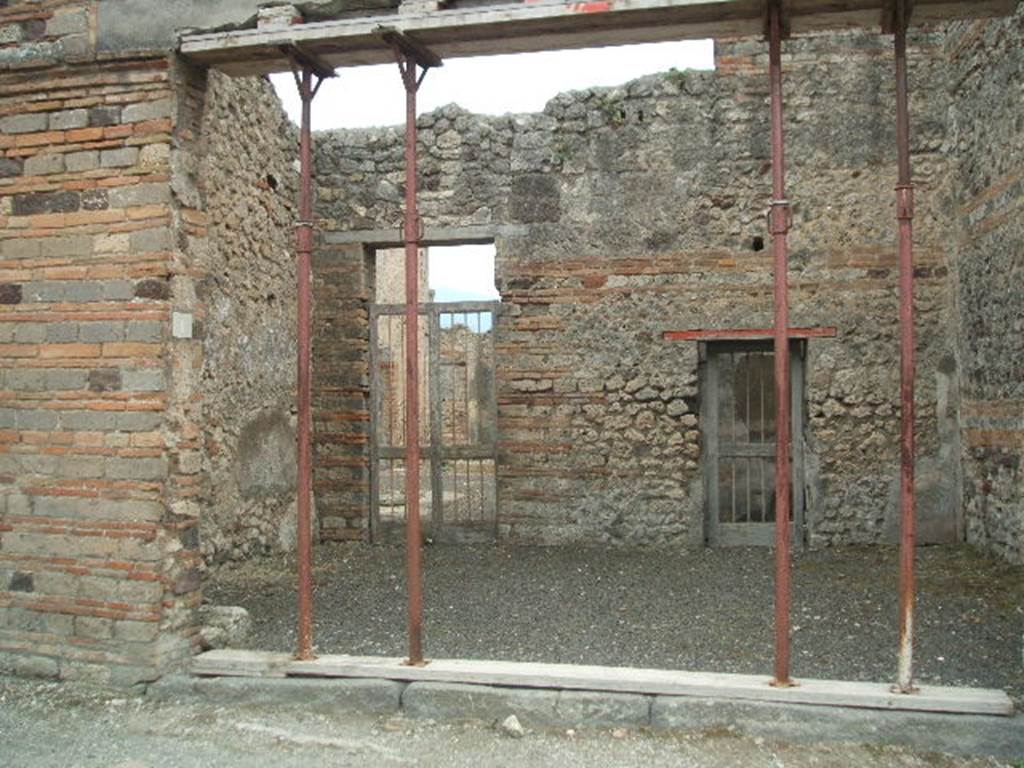 IX.5.1 Pompeii. May 2005. Entrance to shop, with two doorways in the rear wall. One doorway leading to the atrium of IX.5.2, and the doorway on the right, to a rear room (? cubiculum).
