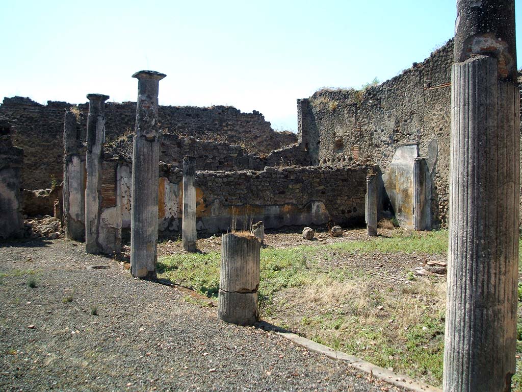 IX.5.14 Pompeii. May 2005. Looking south-west across portico of two-sided peristyle “k”.
According to Jashemski, the portico of the garden was entered directly from the atrium. There was no tablinum.
The portico was supported by four white stuccoed columns on the east, and on the south by six somewhat lower columns.
The two rooms on the east, described by Eschebach as exedra or triclinia, had a good view of the garden.
See Jashemski, W. F., 1993. The Gardens of Pompeii, Volume II: Appendices. New York: Caratzas. (p.237)  
