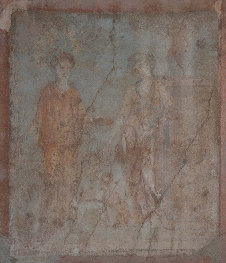 IX.5.14 Pompeii. May 2017. 
Room “g”, central wall painting from east wall of Ariadne and Dionysus with panther and a statue of Pan.
Foto Christian Beck, ERC Grant 681269 DÉCOR.
Kuivalainen’s description is of –
“A composition of two persons, a panther and a statue, outdoors on green terrain with a light blue background.
On the left, a female wearing a yellow/orange tunic stands almost frontally with her weight on her left foot; she has a wreath of ivy on her head; in her right hand she holds a thyrsus, with her left she holds out a patera towards the youth in the middle. He stands with his weight on his right foot, wearing long boots, a pardalis, and a long violet cloak on his left arm; he has a wreath of ivy in his curly hair; in the bend of his left elbow he holds a thyrsus with a small bunch of leaves on top; in his right hand he holds a cantharus, out of which he pours wine into the mouth of a sitting panther with its right foreleg raised. On the right there is a pedestal, the front side of which is decorated with patera, on top of which stands a small dancing faun with hairy legs and hoofs; his right arm is outstretched, and in his left he holds a pedum.”
Kuivalainen comments –
“It is more likely that young Bacchus is depicted in the company of Ariadne rather than Libera, due to the colour of her dress perhaps a reference to flammeum”. (405).
(Note 405 reads – A flame coloured veil worn by Roman brides, e.g. Plin. nat. 21.46.)
See Kuivalainen, I., 2021. The Portrayal of Pompeian Bacchus. Commentationes Humanarum Litterarum 140. Helsinki: Finnish Society of Sciences and Letters, (p.127-8, D5).

