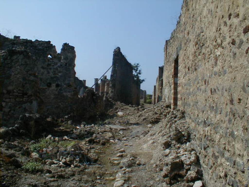 IX.6 Pompeii, on left. May 2006. Unnamed roadway looking west, with south exterior wall of IX.5.16, on right.