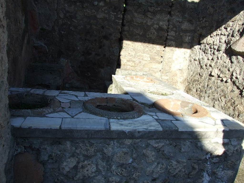 IX.7.13 Pompeii. December 2006.  Counter with urns. In the rear wall is a blocked door that led to the rear.