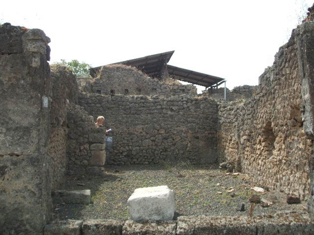 IX.7.23 Pompeii. May 2005. Looking south across caupona to narrow rear room. According to Mau, immediately behind the threshold of the main room, lay a large stone square block of travertine (0.90 long, 0.58 wide and 0.46 high). He thought this probably served as the base for a wooden table, around which the customers would settle down to eat. He also said the threshold of this main room seemed to have been made of wood. See Mau in BdI, 1882, (p.183)
According to Eschebach, the podium used to be on the west side (right of photo) of the caupona, the rear room had the hearth and a window looking into the caupona. See Eschebach, L., 1993. Gebäudeverzeichnis und Stadtplan der antiken Stadt Pompeji. Köln: Böhlau. (p.435)

According to Della Corte, this caupona was attributed to Ti. Claudio Epafrodito, because of the seal/signet brought to light here –
Ti. C(laudius) Ep(aphroditus)    [CIL X 8058,9]. 
He was well noted as producer of wine, one of his numerous named amphora was found in an adjacent atrium.  See Della Corte, M., 1965.  Case ed Abitanti di Pompei. Napoli: Fausto Fiorentino. (S.27 on p.197)
