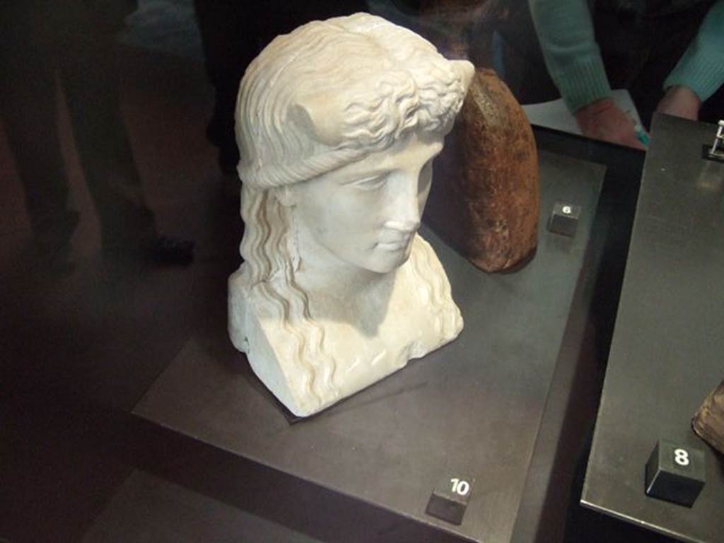 Marble statuette of Iside-Io? Found in IX.7.23, according to Naples Museum card.  Now in Naples Archaeological Museum.  Inventory number 119584. According to Jashemski and Dwyer, this was found in the atrium of IX.7.20, but probably belonged to the peristyle. It was discovered on 28th October 1880, and described as –
Bust for a herm. White marble. Height m.0.21.
The back of the bust is flat and the sides show cuttings for cross-bars.
A river god, with bull’s horns protruding from above temples.
Hair parted down the middle, descends in wavy tresses to chest.
See Jashemski, W. F., 1993. The Gardens of Pompeii, Volume II: Appendices. New York: Caratzas. (p.241)
See Dwyer, Pompeian Domestic Sculpture, pp.71-78.
