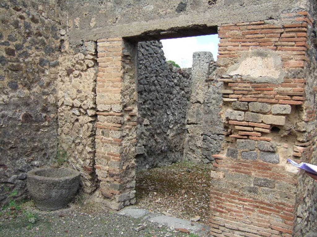 IX.9.6 Pompeii. May 2006. Doorway to cubiculum in north-west corner of atrium.
According to NdS, the doorway to this room was made narrower by the addition of a pilaster formed by rows of masonry bricks and tufa cut in a similar style, on its left. When found, this doorway was furnished with a door, the imprint of which could be seen at the time of excavation, but it could not be saved. The room had a rough signinum floor, and rustic walls. In the west wall was a semicircular niche, plastered entirely in white stucco studded with coloured specks, which could have been flowers. In this room, some amphorae were found (see NdS, 1887, p.561) containing lime. In the rustic plaster, on the pilaster between the entrance corridor and the doorway to the room (right in picture above), graffiti were found. They read –
IVCVNDVS        and          QVOIVS
 VIINVS                                LABORE
 VITALIS
See Notizie degli Scavi, 1889, p.123.

