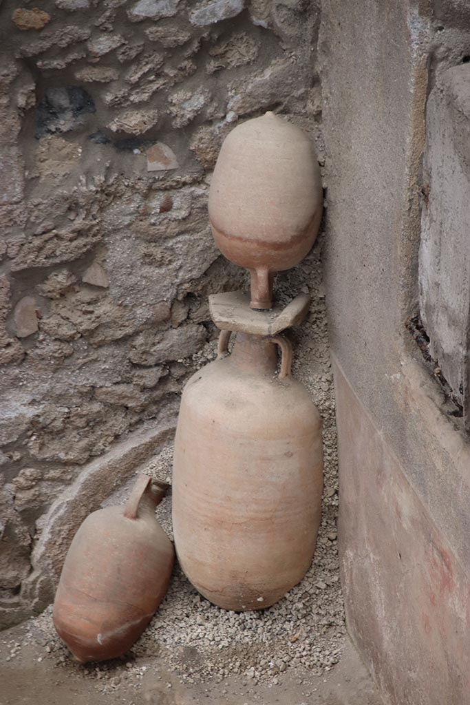 IX.12.4 Pompeii. October 2024. 
Small courtyard “m”, north-east corner with amphorae. Photo courtesy of Klaus Heese.
