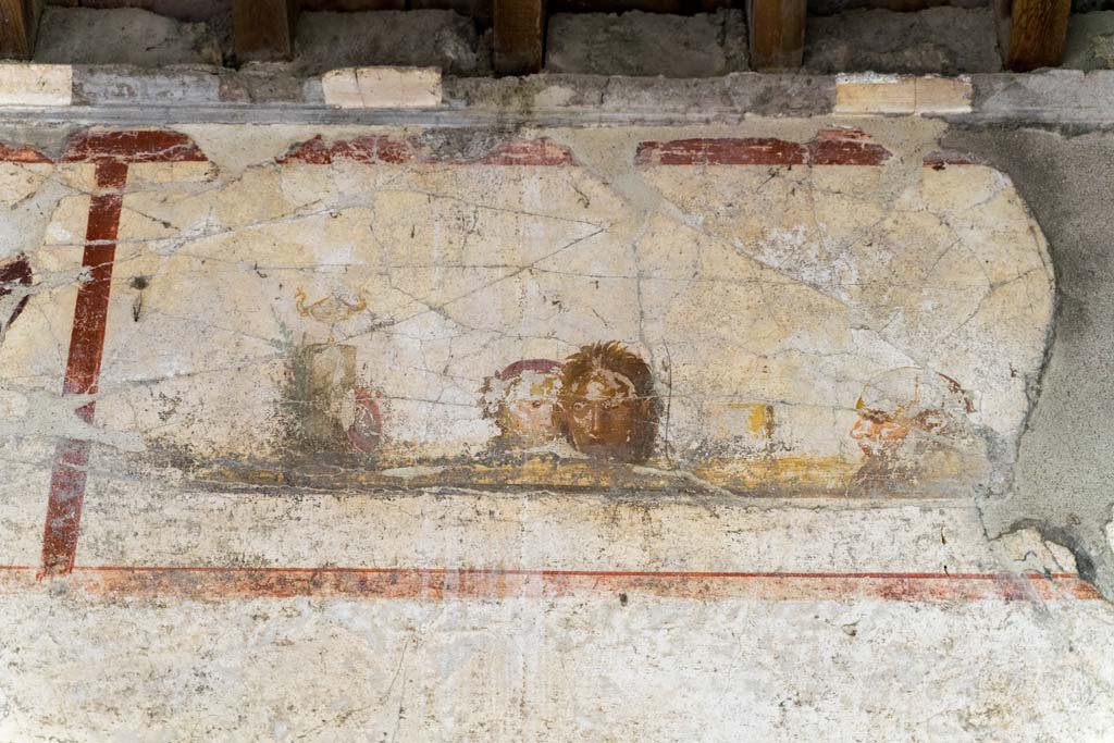 IX.13.3 Pompeii. October 2021. 
Room 9, detail of panel on upper east wall with painting of masks or faces. Photo courtesy of Johannes Eber.
