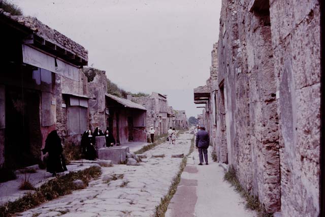 Via dell’Abbondanza, Pompeii. 1964. Looking east between IX.7 and I.6.   Photo by Stanley A. Jashemski.
Source: The Wilhelmina and Stanley A. Jashemski archive in the University of Maryland Library, Special Collections (See collection page) and made available under the Creative Commons Attribution-Non Commercial License v.4. See Licence and use details.
J64f0917
