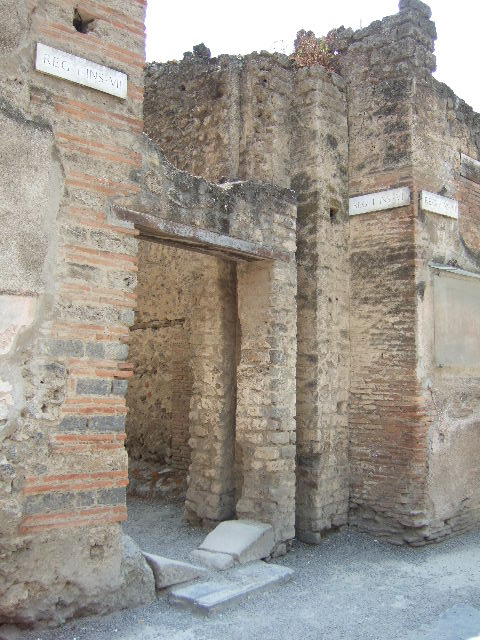 Via dell’ Abbondanza, south side. May 2006. Entrance to Vicolo di Paquius Proculus and water tower between I.7 and I.6. 