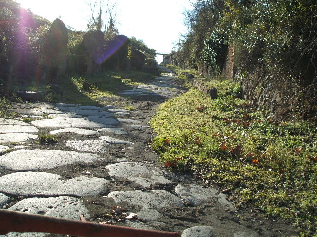 Via di Nola. December 2004.  Looking west between III.11 and IV.5 from Nola Gate. On the right is the entrance of the unnamed vicolo on the north side that led around the inside of the city walls.

