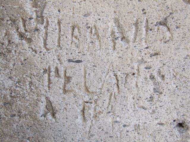 Vicolo degli Scheletri, Pompeii. December 2018. 
Stone block with inscription at corner of Vicolo della Maschera and Vicolo degli Scheletri. 
Photo courtesy of Aude Durand.

