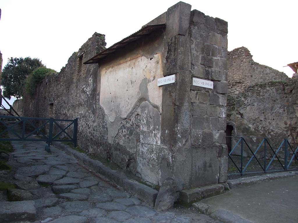 Vicolo dei Dodici Dei between VIII.5 and VIII.3, west side with remains of painted street shrine. December 2006. 
Looking south from Via Dell’Abbondanza. 
