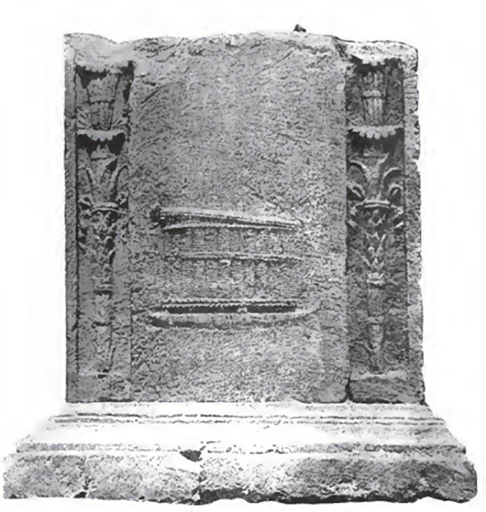 NGH Pompeii. 1910 photo of south side of altar on Schola tomb.
According to Spano, this is a mystical chest, made of rushes, cylindrical, wide, and supported by feet, of which three are visible. 
The head of a snake is lifting the cover. This side is framed by two great torches.
This symbolises that the buried person had been in initiated in life into the mysteries of Dionysus.
See Notizie degli Scavi di Antichità, 1910, p. 395-6.
