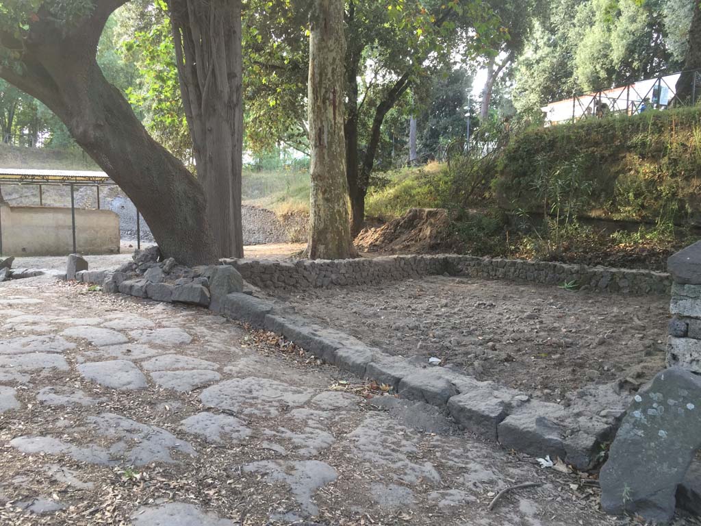 August 2016. Photo courtesy Stephen Kay, British School at Rome.
In 2016 the excavation of a rectangular structure was completed, built just behind the funerary monument of Aesquillia Polla. Variously described by earlier research as a funerary precinct, garden or ustrinum, the 2016 excavation sought to understand the role of this structure, built in a prominent position opposite the Nolan Gate. Once the excavation had removed layers dating to activity of the early twentieth century, which included the burial of a dog and the loss of several terracotta smoking pipes, the work revealed large deposits of construction material used to raise the level beneath the building. However, the 2016 excavation did not record any cremations, supporting the theory of a late construction that was not used before the eruption of AD 79.
See https://britishschoolatrome.wordpress.com/2016/09/08/digging-pompeii-the-2016-summer-excavations/
