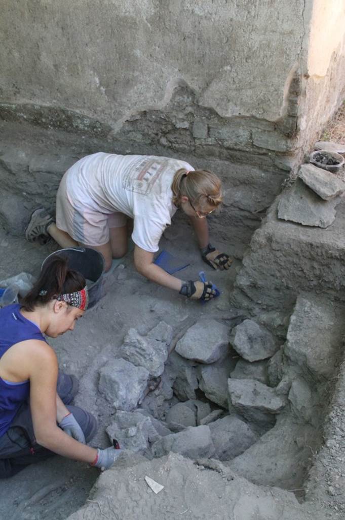 NGOF Pompeii. August 2017. Cremation 0.5m to the north of the tomb of Obellius Firmus was placed inside a pit lined with tufa stone blocks. 
The coarseware cremation urn was sealed by an upturned bowl, and the lid of the urn was covered by ash and hundreds of fragments of a spectacular bone funerary bed.
There was no burial marker.
Photo by Charles Avery, courtesy of British School at Rome.

